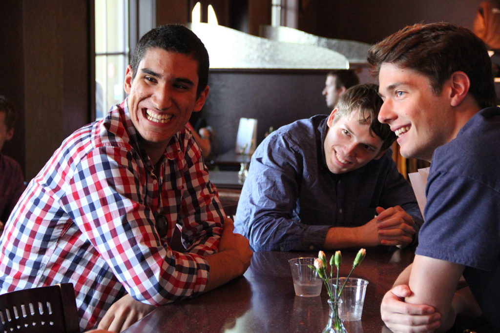 Three members of the Fellows program are smiling and sitting together in a restaurant.