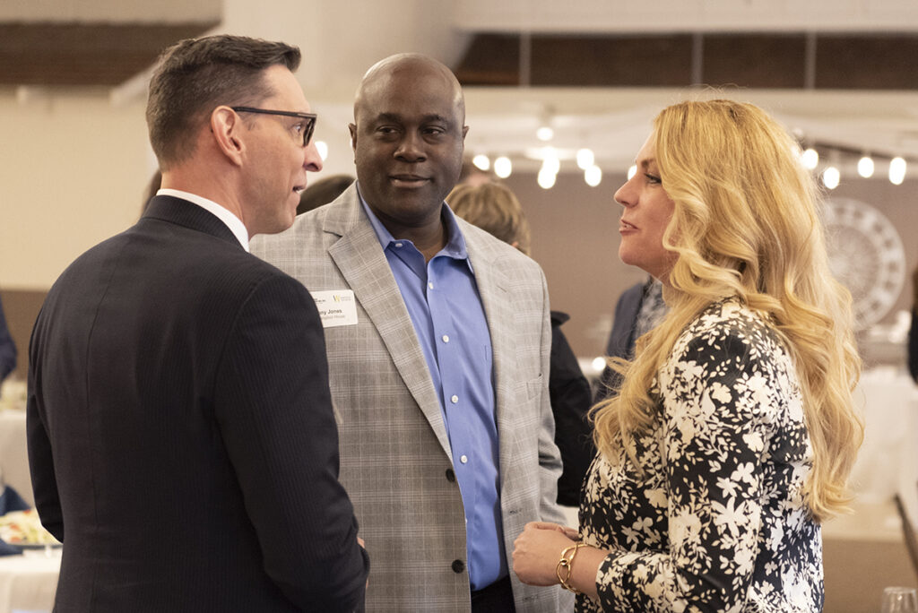 two men and one woman having a discussion at Champions of Change Awards Luncheon