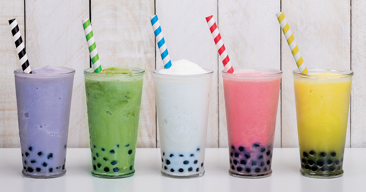 row of five drinking glasses holding colorful drinks and paper straws