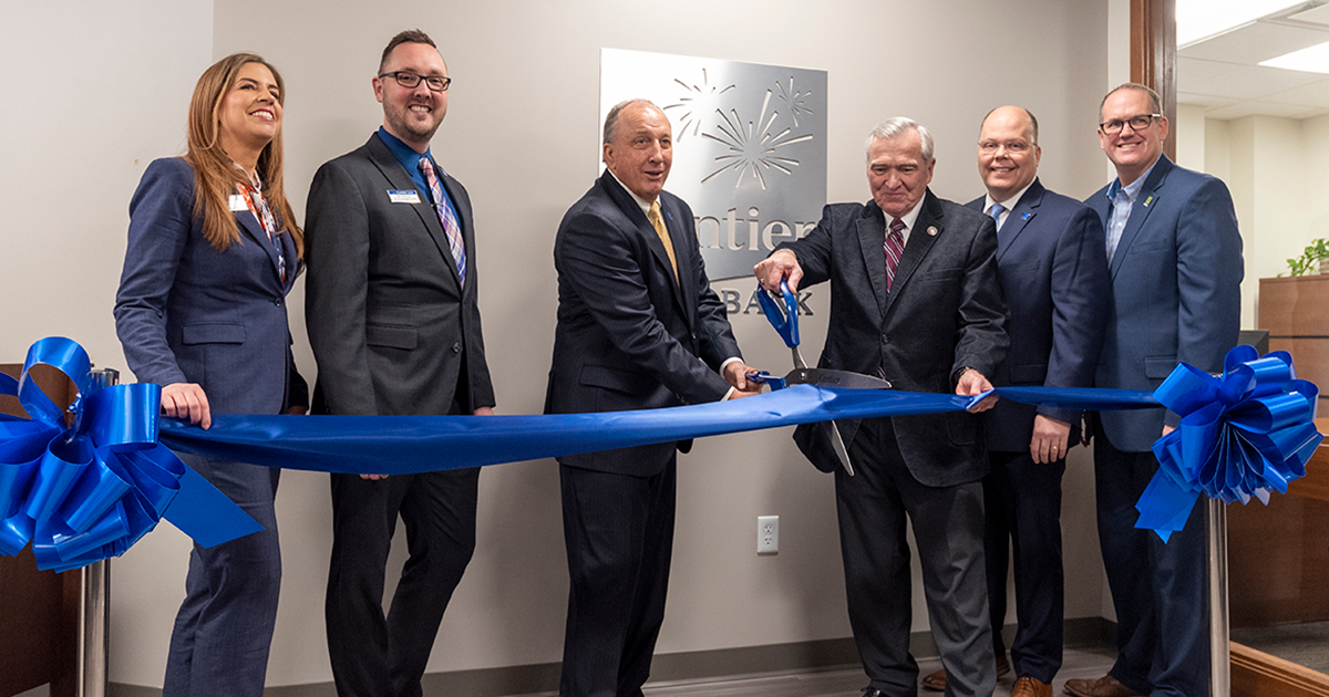 group of people cutting a ceremonial ribbon to open new bank location