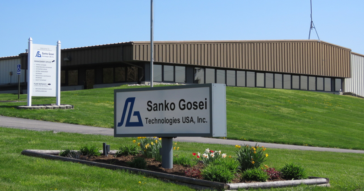 exterior photo of an industrial building with a sign in the foreground