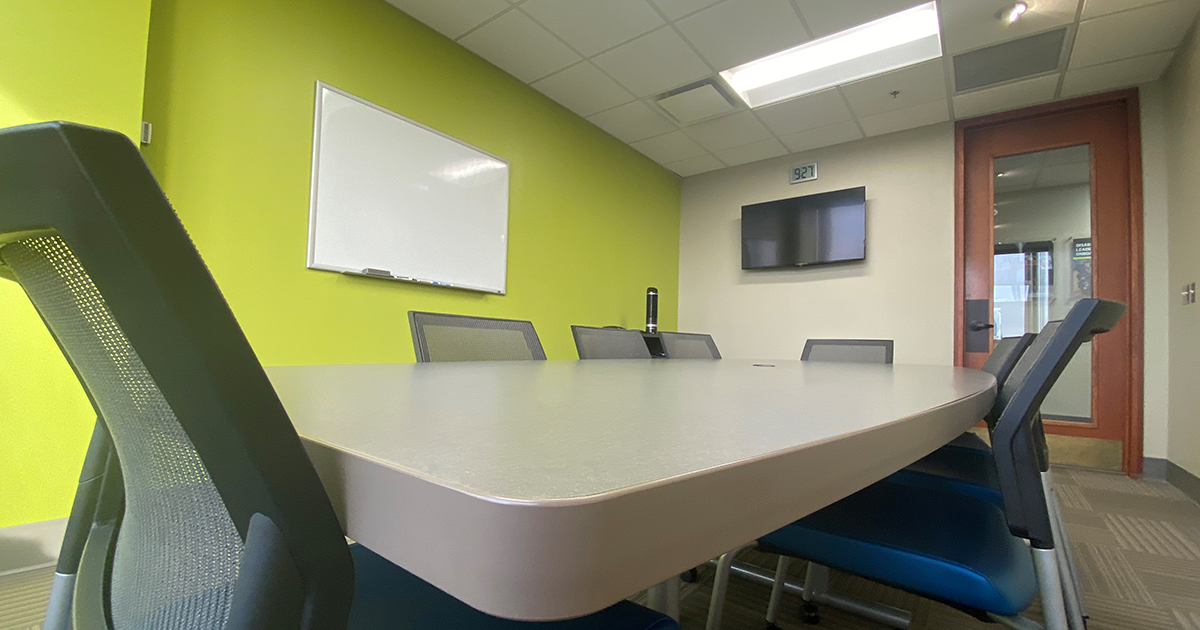Photo of a table, chairs, dry-erase board, and TV in the Doermer East conference room