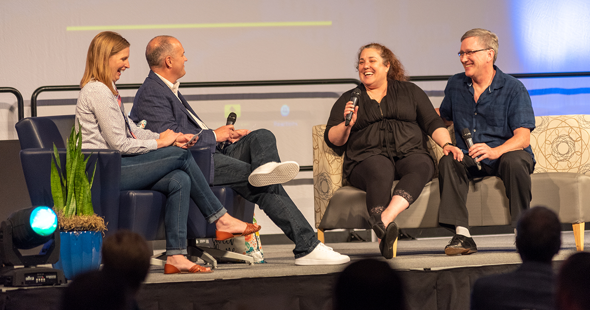 Four people have a Q&A session on stage at the GFW Inc. Annual Meeting event