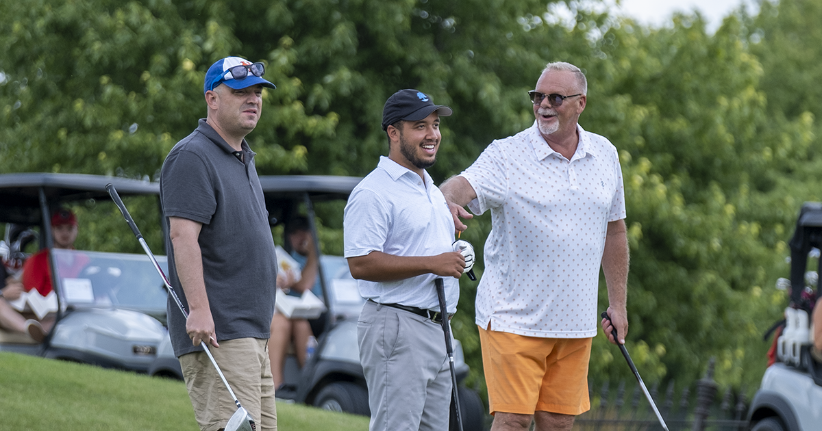 Three teammates chat while they wait to tee off at the Greater Golf Open