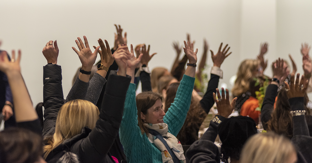 A crowd of people wave their hands in the air during a GFW Inc. Women's Network event