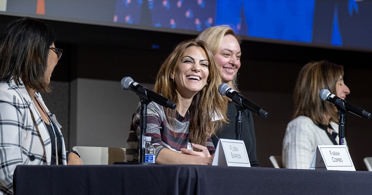 Four people smile while participating in a panel discussion