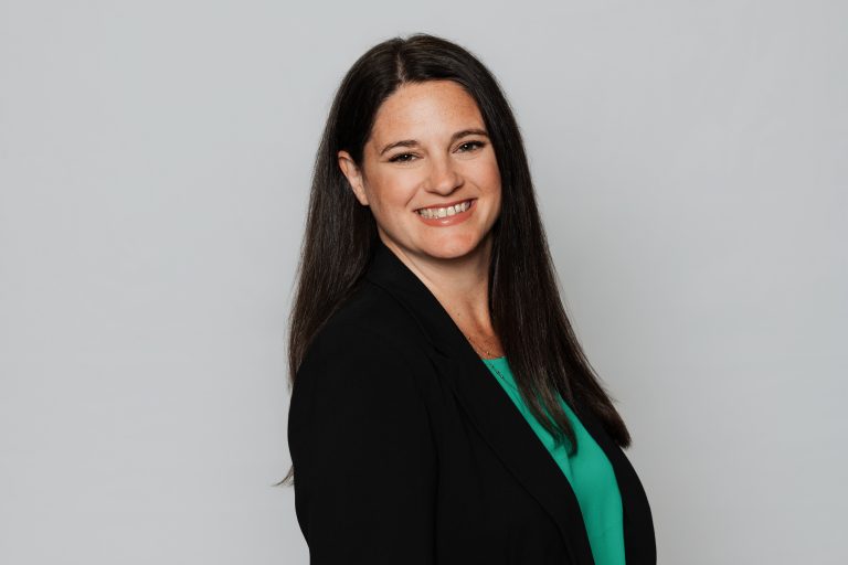 Melissa Beber Headshot, wearing black blouse and green shirt.