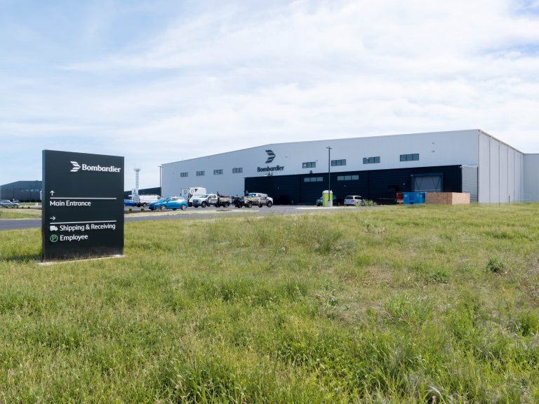 Bombardier Building and Hanger with sign in foreground.